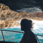 Blue Cave tour Kotor. Mystical photo of a Good Hope Tours speed boat with a silhouette of a guest looking at the sea through the exit of the Blue Cave