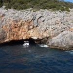 Blue Cave tour Kotor. Blue Cave by Good Hope Tours, with rocks and sea in front of the entrance, and a speed boat entering the cave
