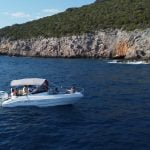 Blue Cave tour Kotor. Drone view of a Good Hope Tours speed boat with tour guests waiting to enter the Blue Cave, with the sea and cave entrance in the background