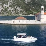 Our Lady of the Rocks - A Timeless Symbol of Faith and Resilience. Drone view of a Good Hope Tours speed boat near Our Lady of the Rocks island, with the sea in the background - Boka Bay