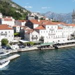 Drone view of Perast, showing historic buildings, the coastline, and a Good Hope Tours speed boat in the sea