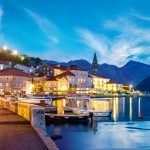 Scenic view of Perast at dusk, showcasing historic buildings and the coastline with the sea in the foreground